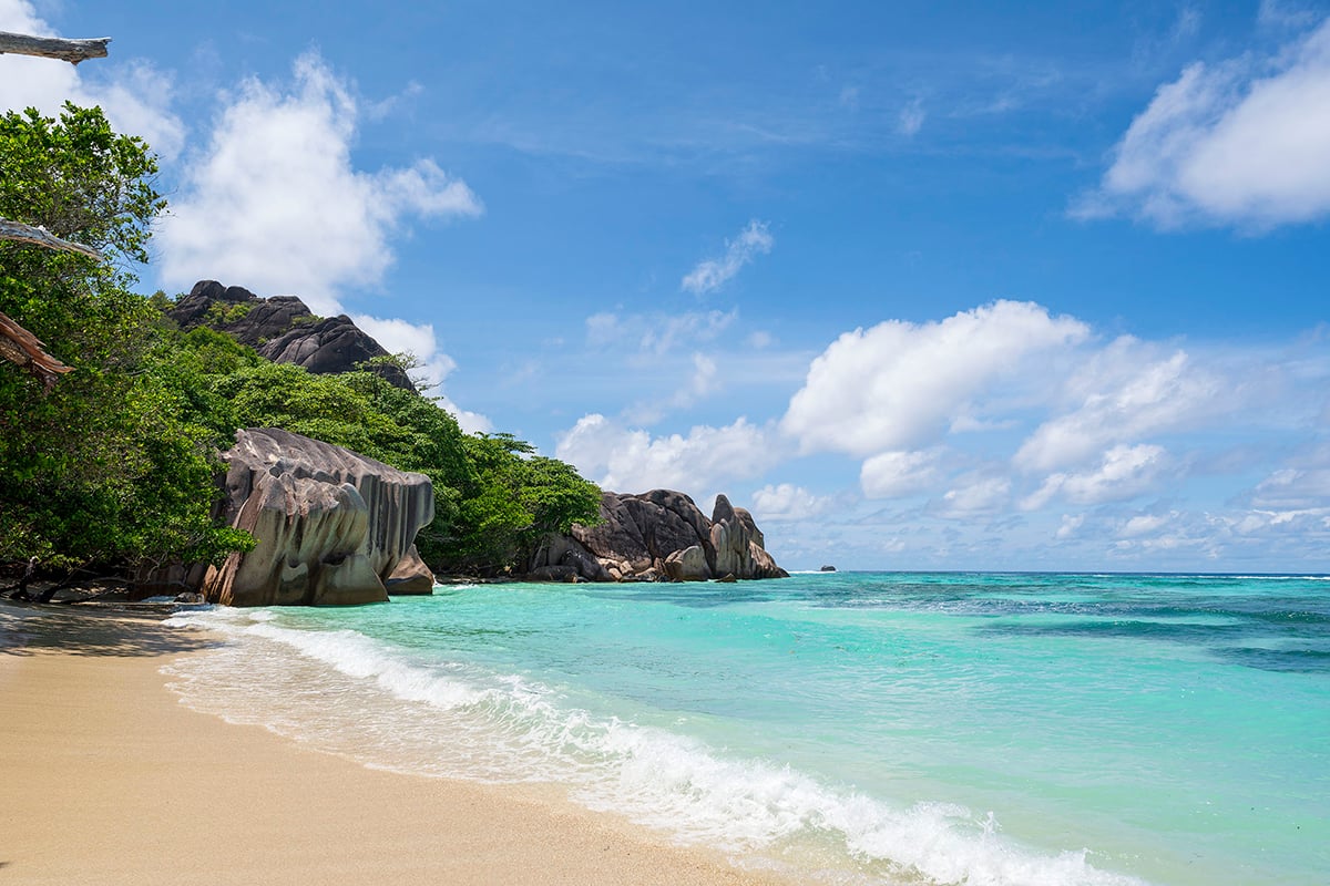 turquoise waters lapping up onto the water sand of Anse Source d'Argent Beach in La Digue, Seychelles