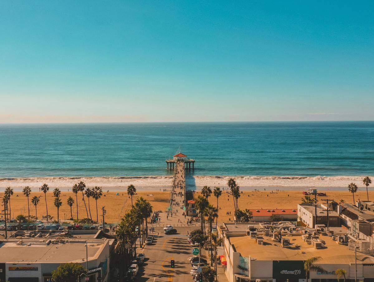 waves lapping up against the shore with palm trees blowing in the wind in Manhattan Beach, Los Angeles, California