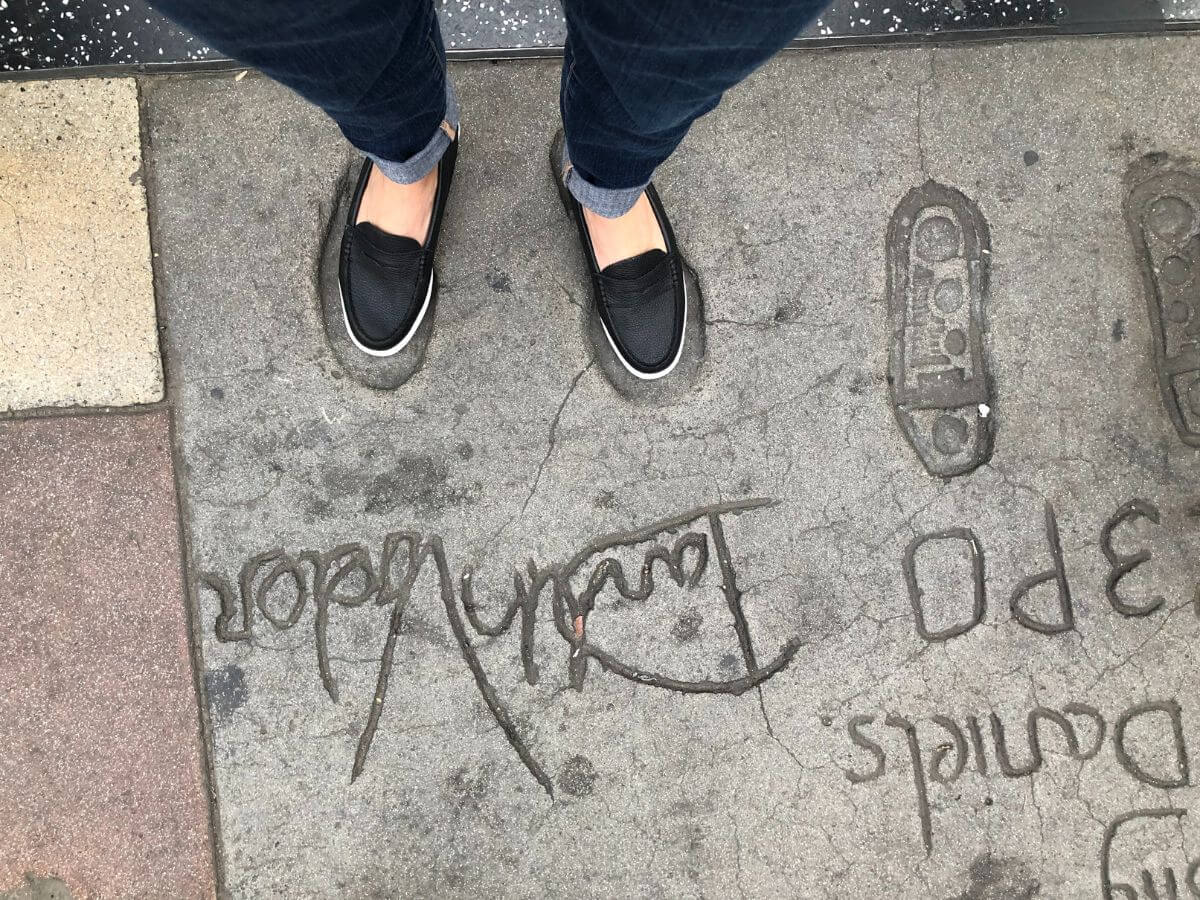 traveler putting her feet in the molds of the famous handprints and footprints at the TCL Chinese Theatre during a 3 day trip to Los Angeles, California