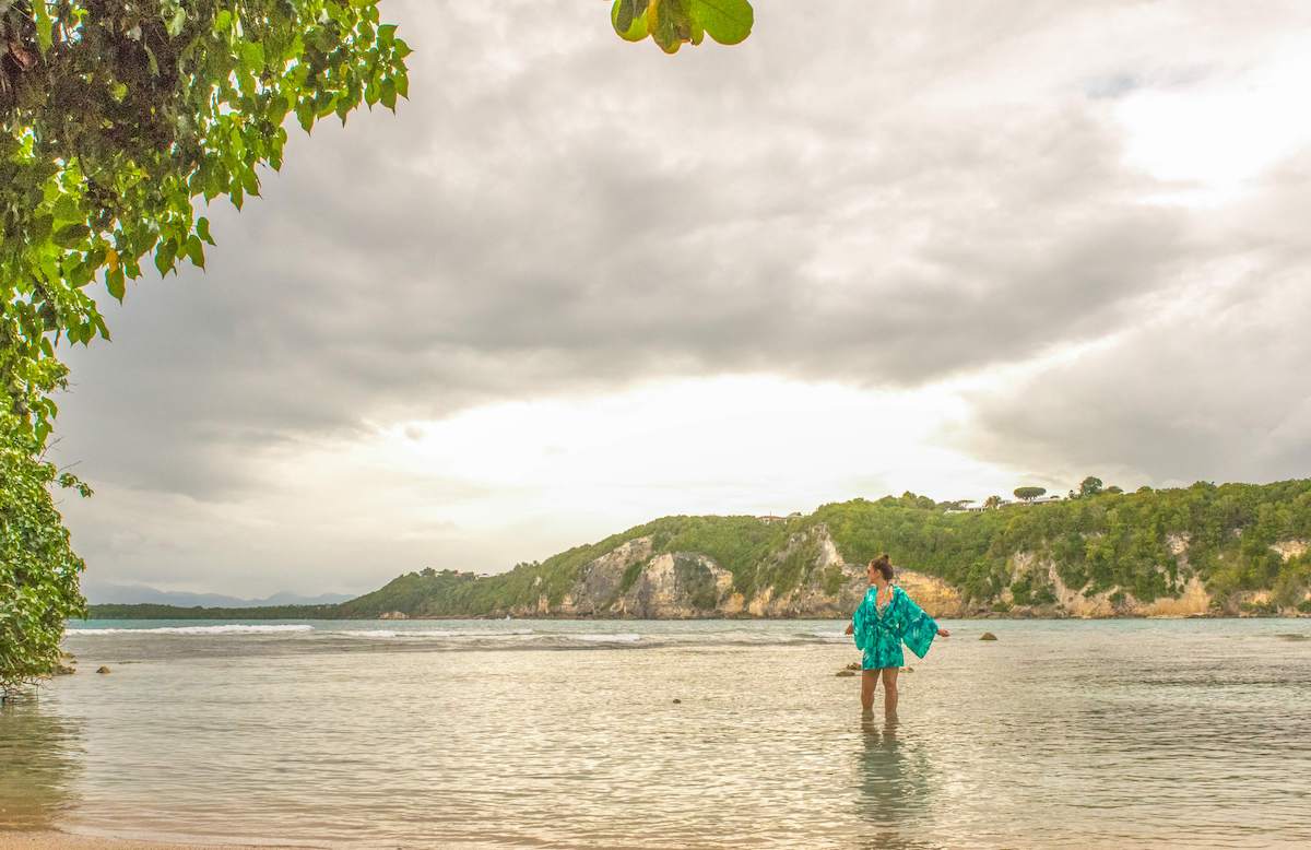 solo female traveler wading through the water at the stunning Plage de Bois Jolan (Sainte-Anne) in Guadeloupe, Caribbean