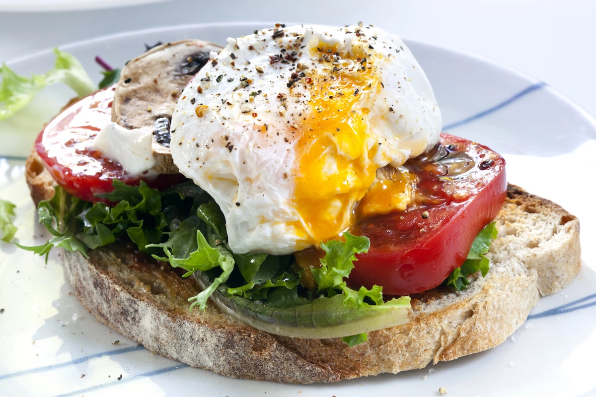 a popular NYC boozy brunch dish of a slice of sourdough toast topped with a poached egg