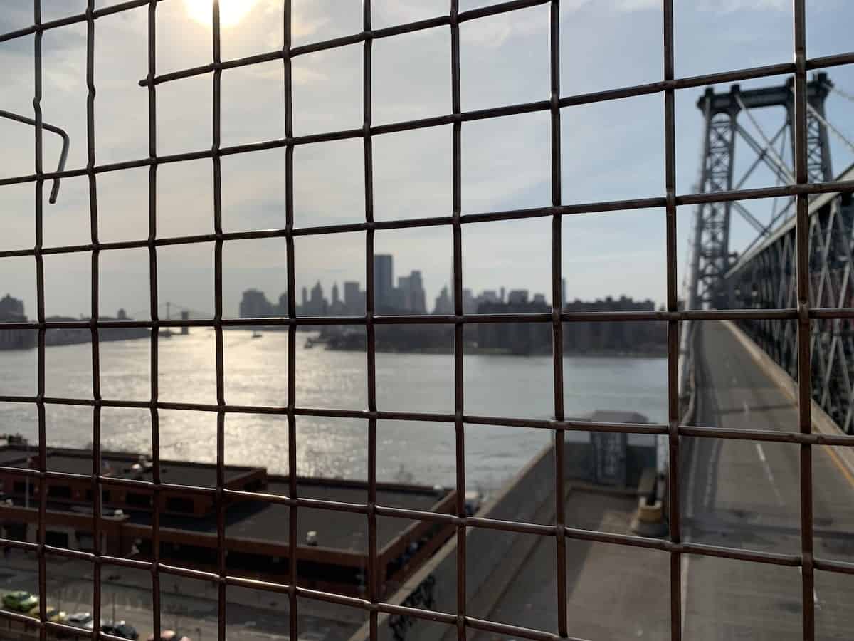 woman looking out over the East River while crossing the Williamsburg Bridge