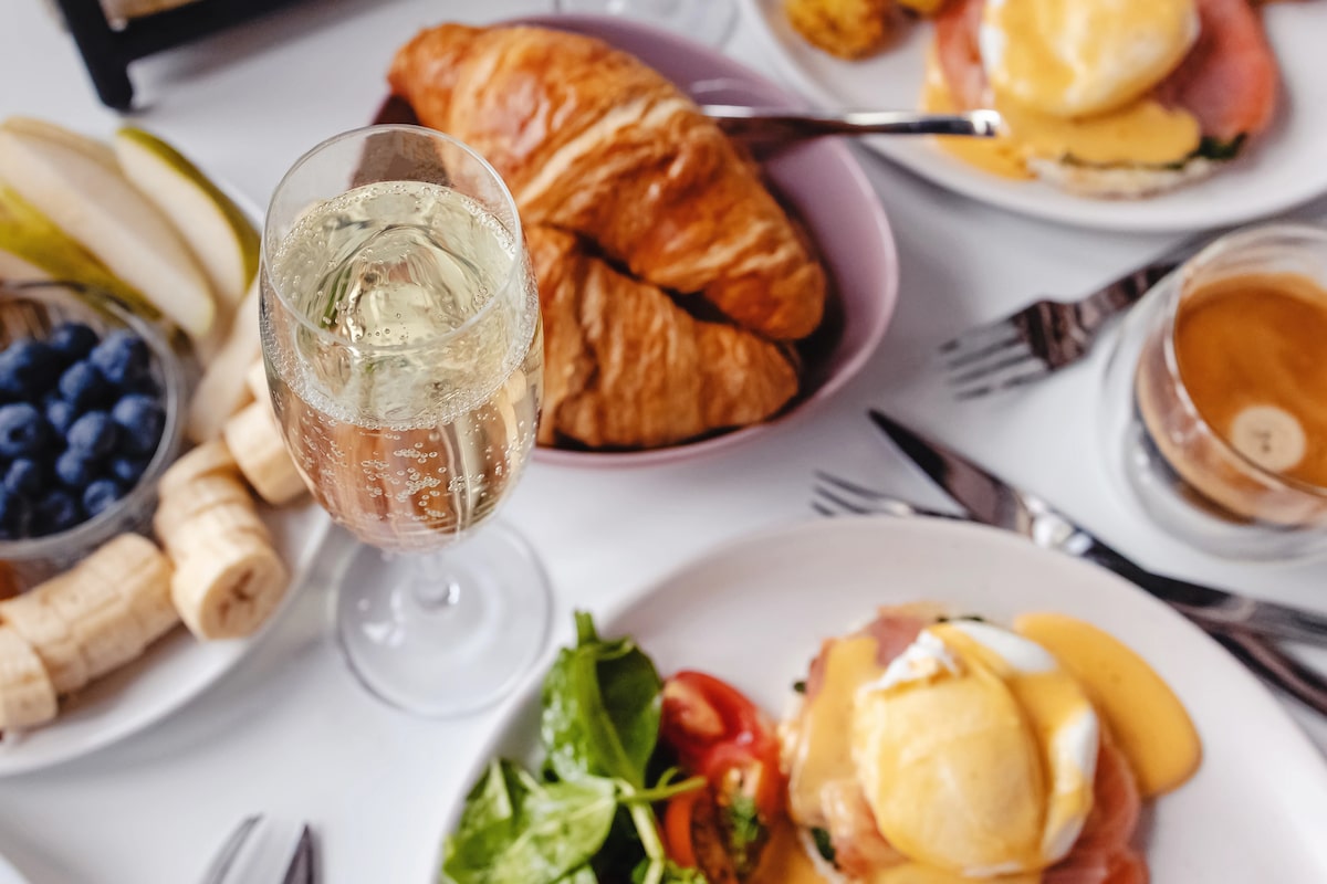 table showcasing a variety of brunch dishes like eggs Benedict and croissants paired with glasses of Champagne