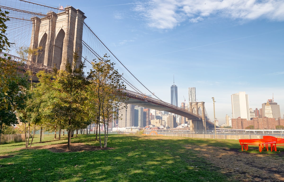 view of the Manhattan skyline and Brooklyn Bridge from Brooklyn Bridge Park in DUMBO, NYC