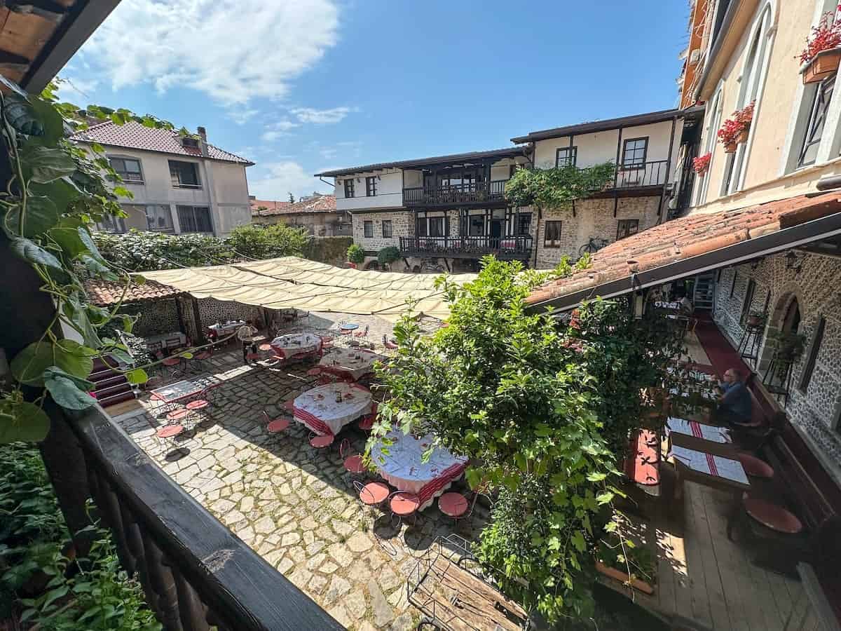 Traditional Albanian-style courtyard at Hotel Tradita in Shkodër, with stone pathways, shaded dining tables, and charming historic architecture.