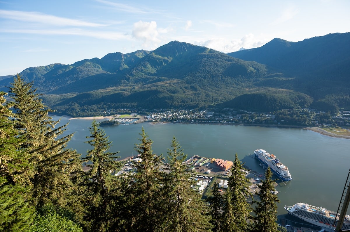 A sweeping aerial view of Downtown Juneau, Alaska, and the Gastineau Channel with cruise ships docked at the port, as seen from the top of Mount Roberts via the Goldbelt Tram.